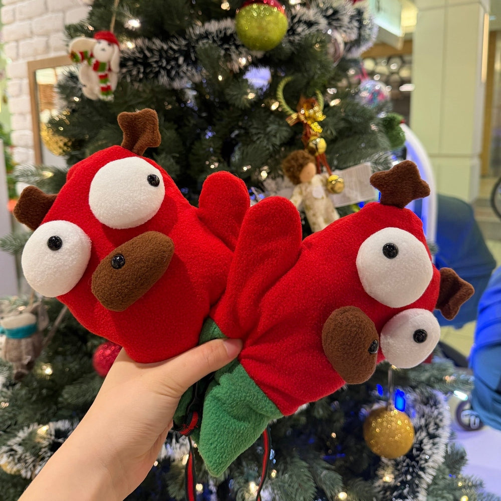 Red plush reindeer slippers held in front of a decorated Christmas tree.