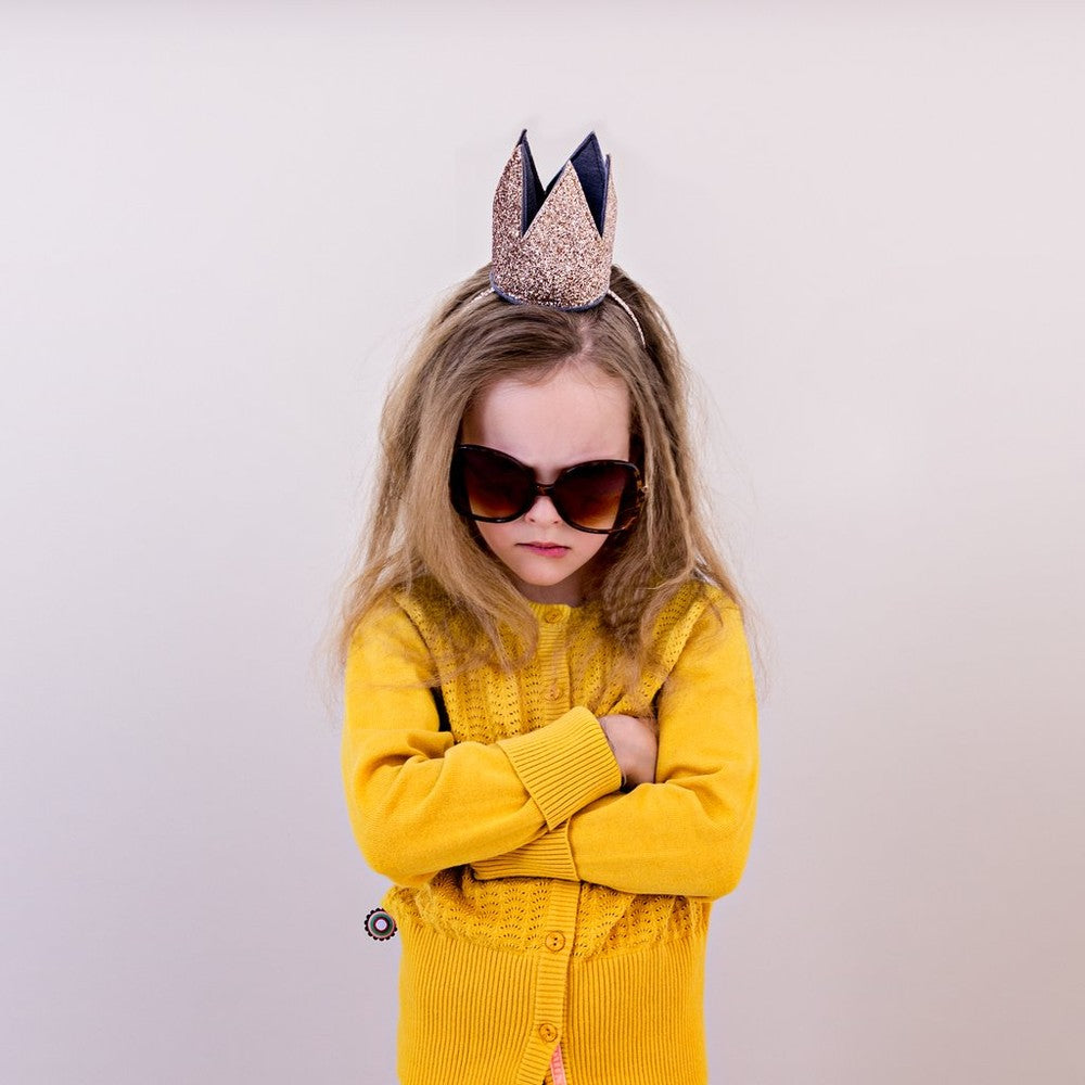 Mimi & Lula Glitter Crown Alice Gold on a girl wearing oversized sunglasses and a yellow cardigan.
