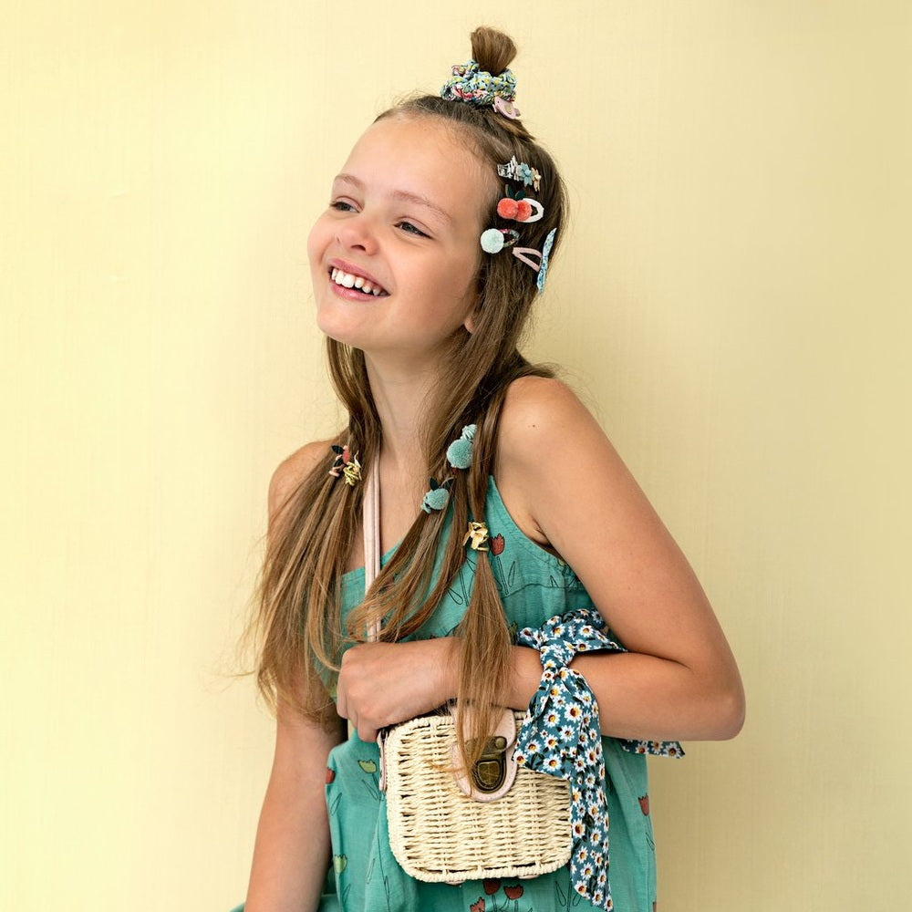 Mimi & Lula mini wicker basket crossbody bag worn by girl in teal dress with floral scarf accents