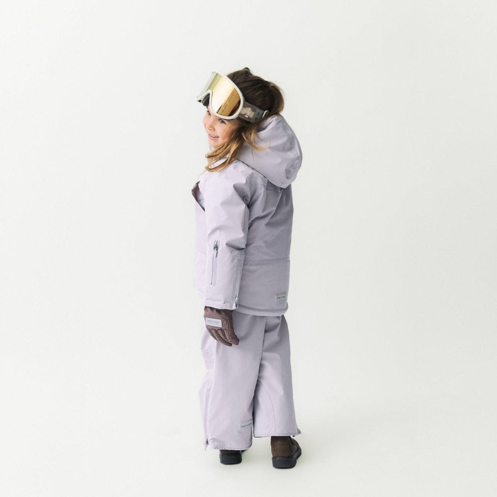 Mini A Ture Matadane Ski Tech Jacket Grs Purple Raindrops worn by a child in lavender hooded ski suit with goggles.