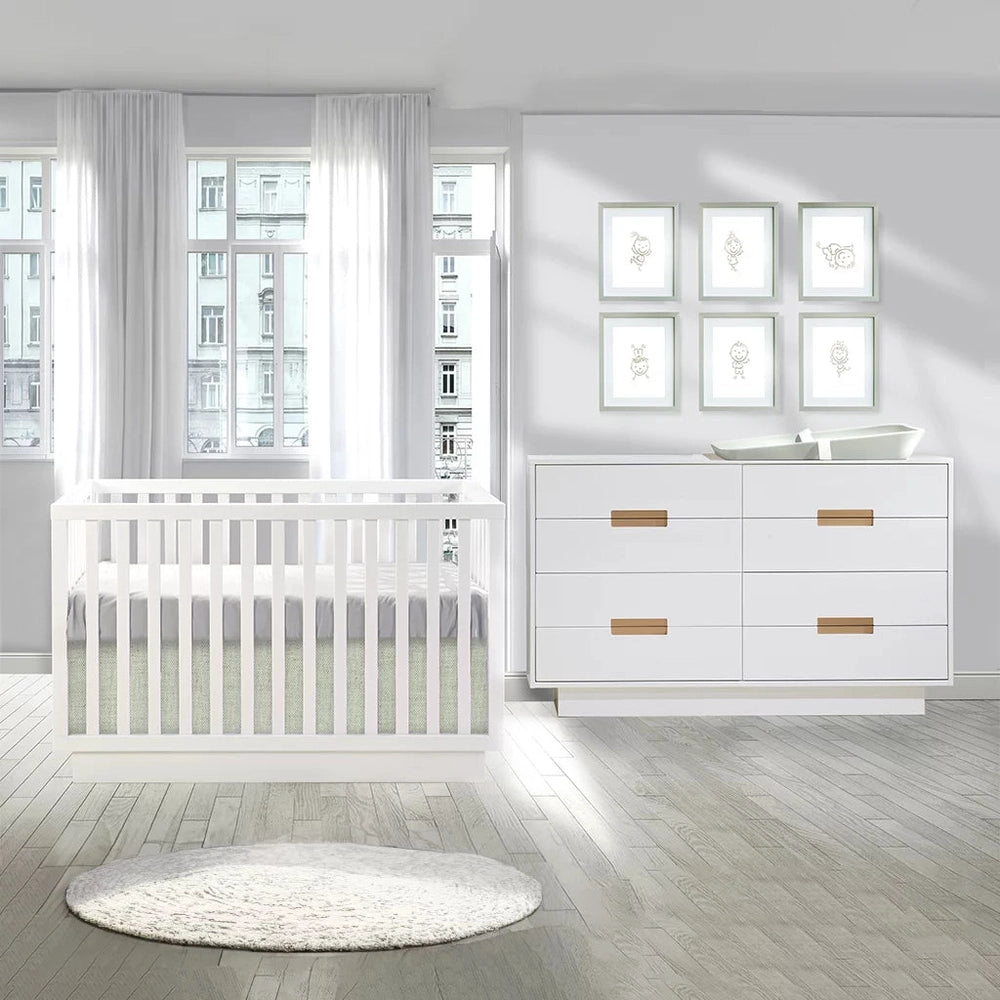 Natart Signature Series Como 8-Drawer 52in Double Dresser in white with wood pulls beside a white crib in a bright nursery.