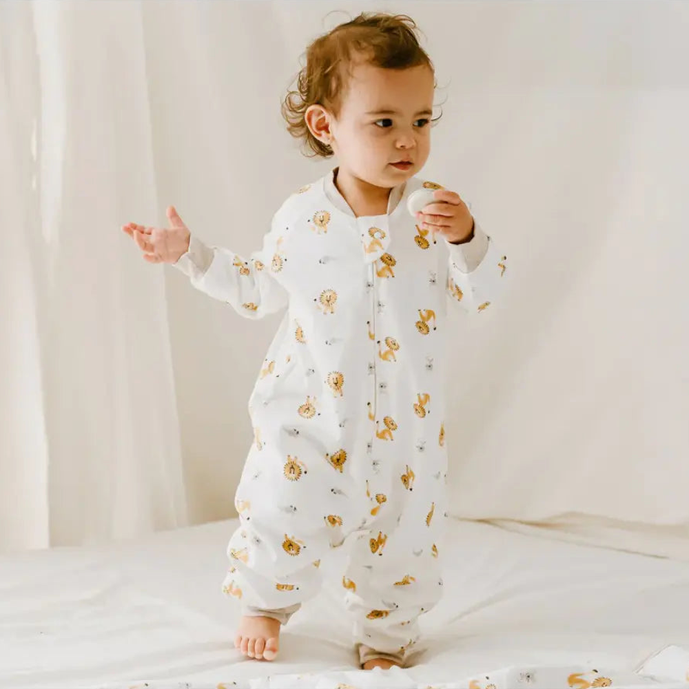 Nest Designs Avocado Bamboo Long Sleeve Footed Sleep Bag 1.0 Tog The Lion & The Mouse; toddler stands in a white sleep sack.