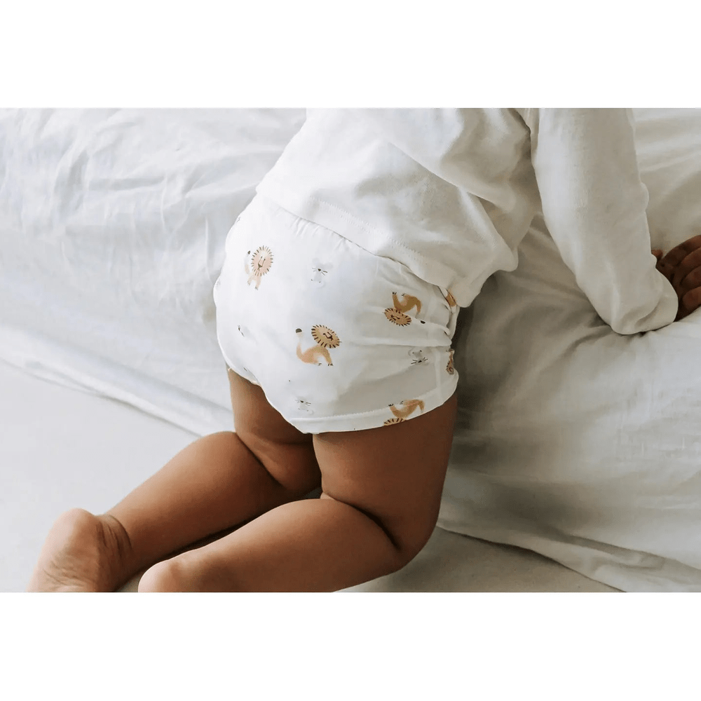 Nest Designs Bamboo Girls Boy Short Underwear 2-Pack worn by a crawling baby on a white bed, white with lion and goose prints.