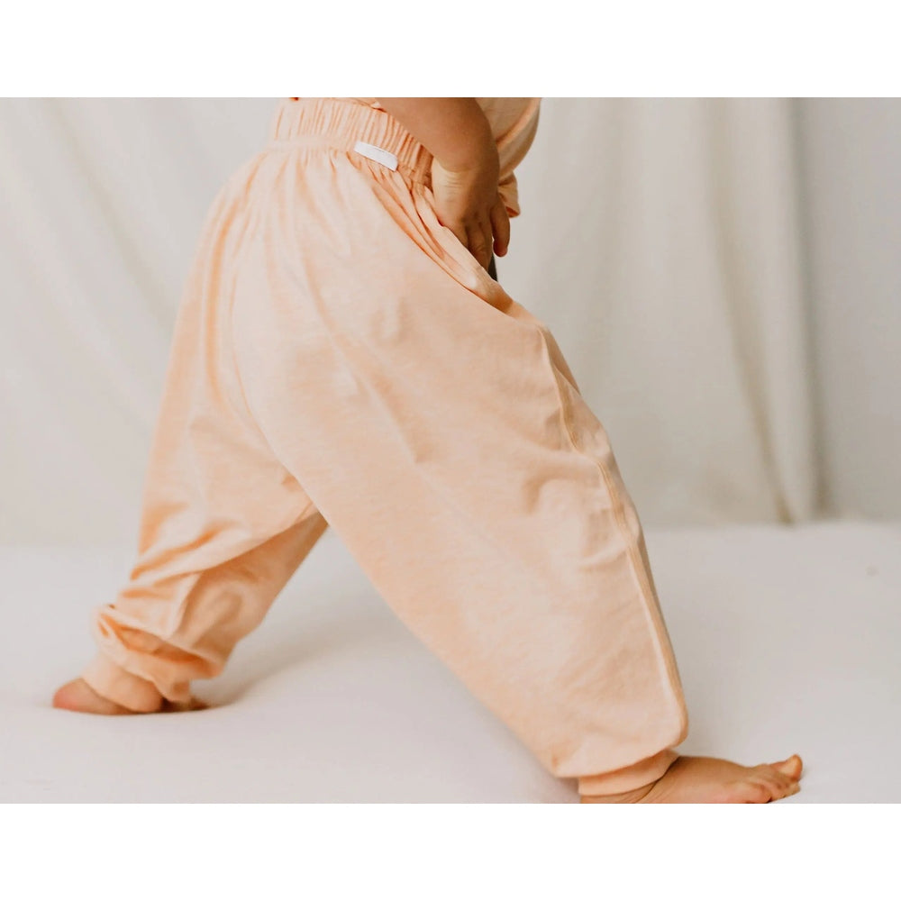Nest Designs Bamboo Jersey Harem Pants Pantone Bellini peach; a toddler walks, showing soft, relaxed fit with elastic waist.