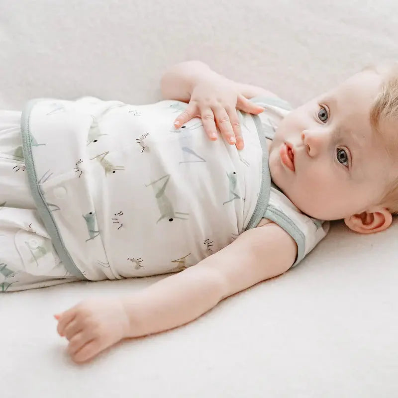 Nest Designs Bamboo Jersey Swaddle Sleep Bag 0-6M: baby lying on back swaddled in white sleep bag with grey trim and insect pattern