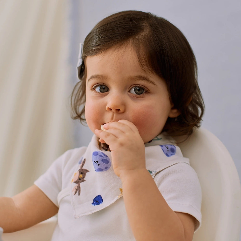 Nest Designs bamboo muslin bandana bib Evening Bounty on a toddler with a white shirt and blue animal prints