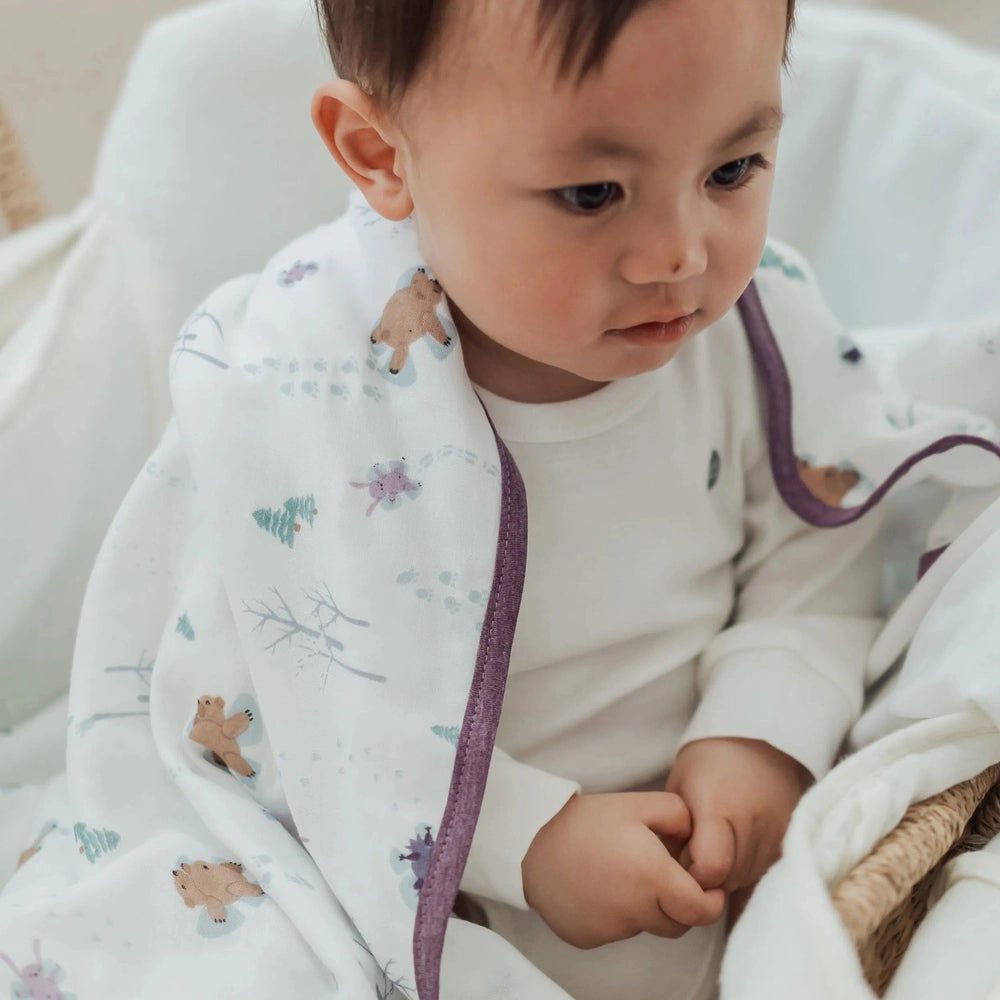 Nest Designs Bamboo Muslin Small Nesting Blanket 120x120, white with purple edge, baby swaddled.