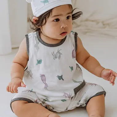 Nest Designs Bamboo Pima Sleeveless Romper The Tortoise & The Hare, white with gray trim, baby sits wearing a soft animal-print romper.