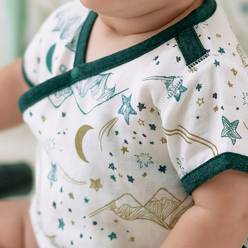 Nest Designs Bamboo Short Sleeve Kimono Onesie Stars White worn by a baby, emerald trim with star pattern.