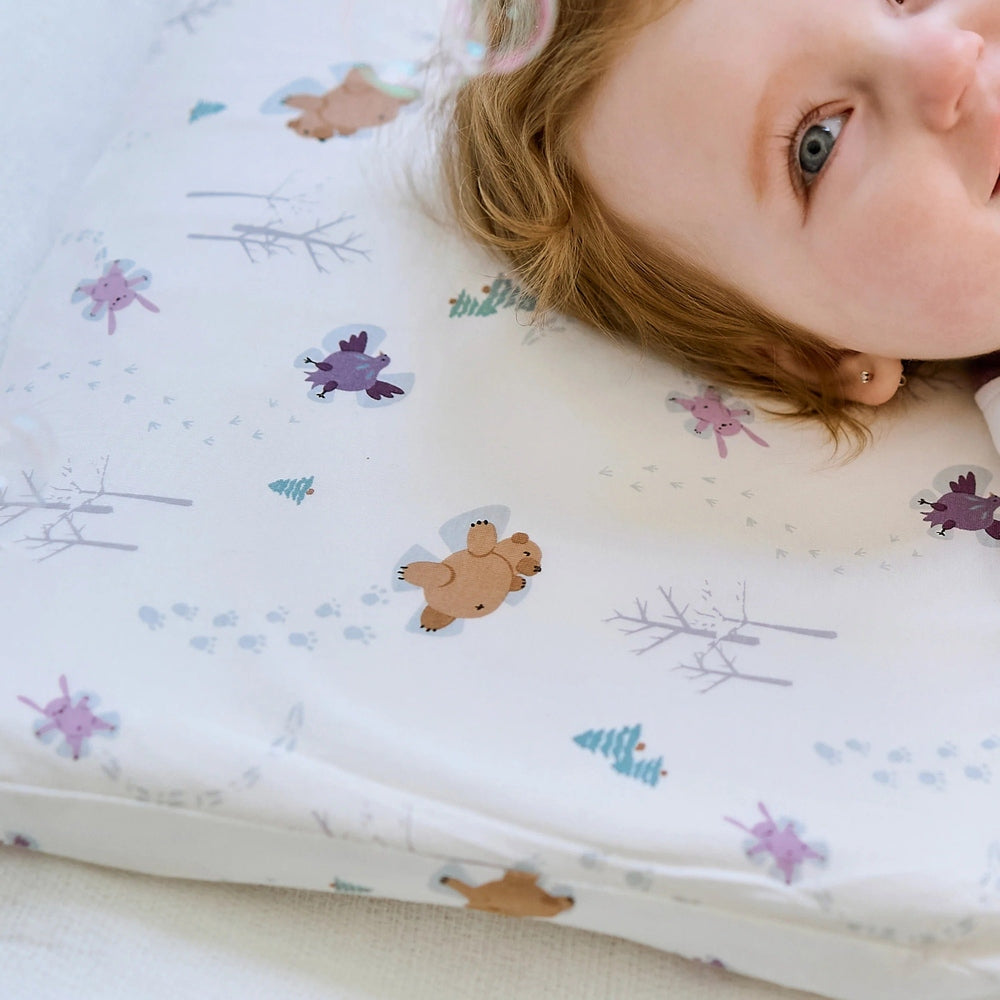 Nest Designs Bamboo Toddler Pillow With Pillowcase Snow Angels; a child rests calmly on the soft, printed pillow.