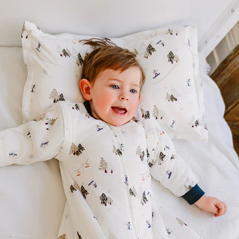 Nest Designs Bamboo Toddler Pillowcase Chills N' Thrills, white with winter print, on a smiling toddler resting on a pillow