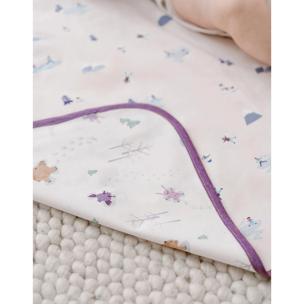 Nest Designs Cotton Waterproof Change Pad Large Snow Buddies white pad with purple edge on a textured rug