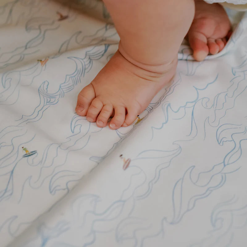 Nest Designs cotton waterproof change pad, surf camp pattern, baby feet on padded surface