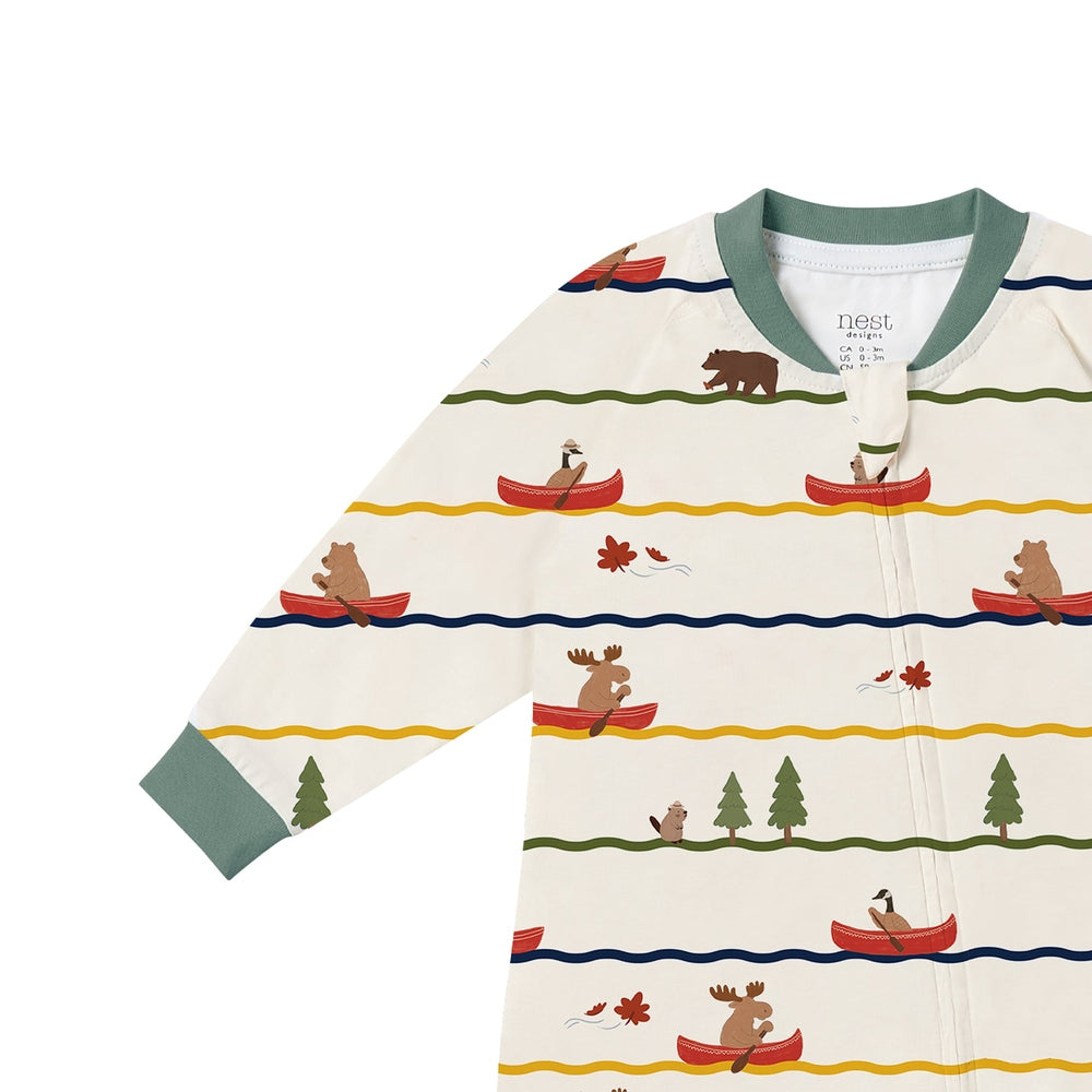 Nest Designs Canoe Do It long-sleeve footed sleeper in cream with green cuffs, laid flat.
