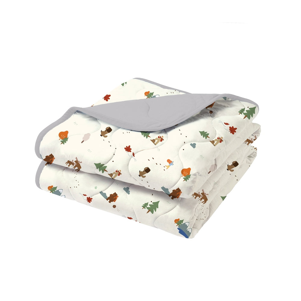 Nest Designs Small Cozy Blanket folded neatly, white with colorful woodland print and gray trim, ready to warm a bed.