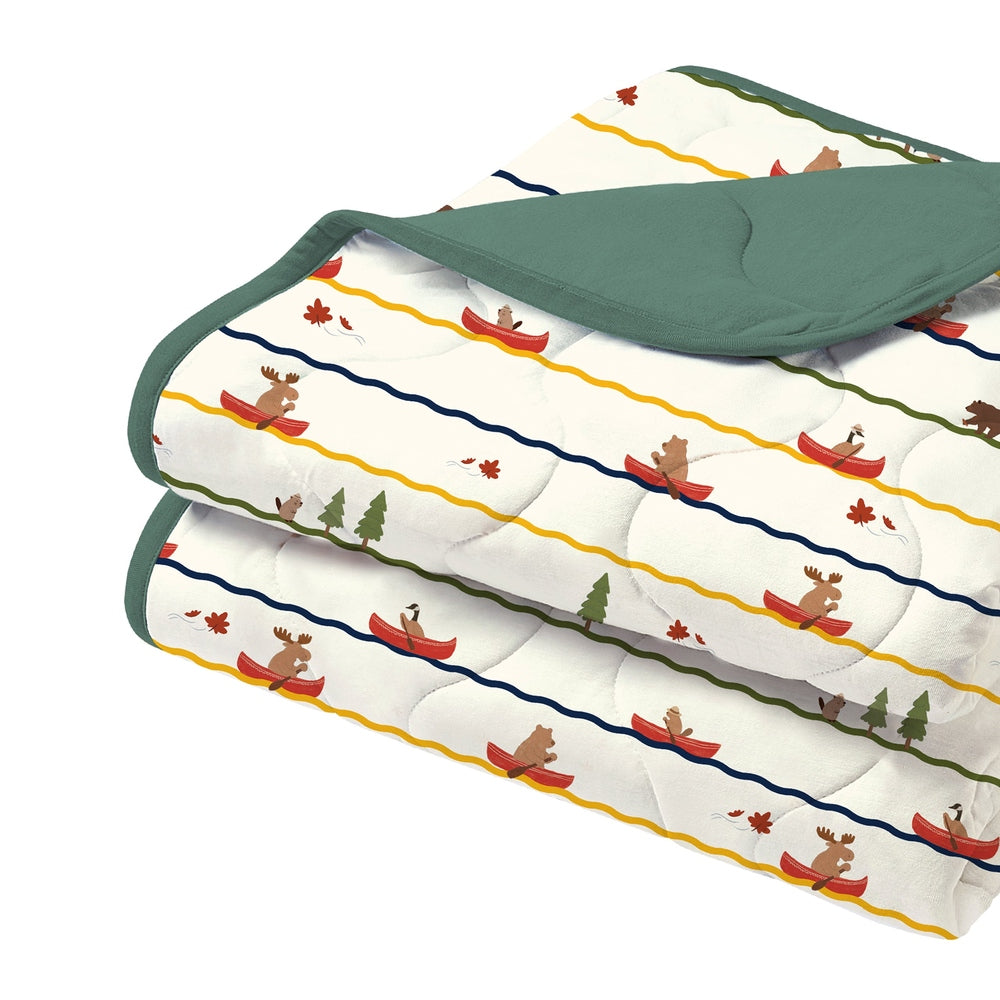 Nest Designs Small Cozy Blanket folded to reveal green edging and a playful canoe-moose print.