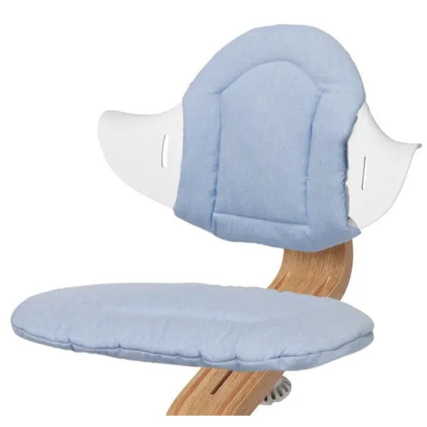 NOMI Highchair Cushion in light blue fabric attached to a wooden high chair, showing padded backrest and seat.