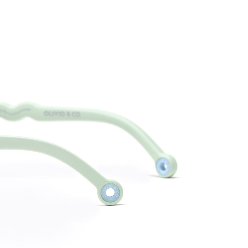 Olivio & Co round kids' sunglasses in natural light green, curved arms with blue end caps on white surface.
