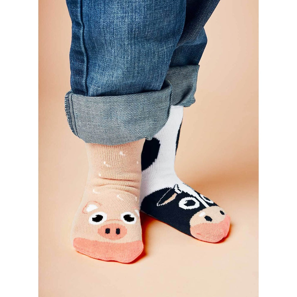 PALS SOCKS Cow & Pig mismatched socks; a child models peach pig sock and black cow sock with rolled jeans.