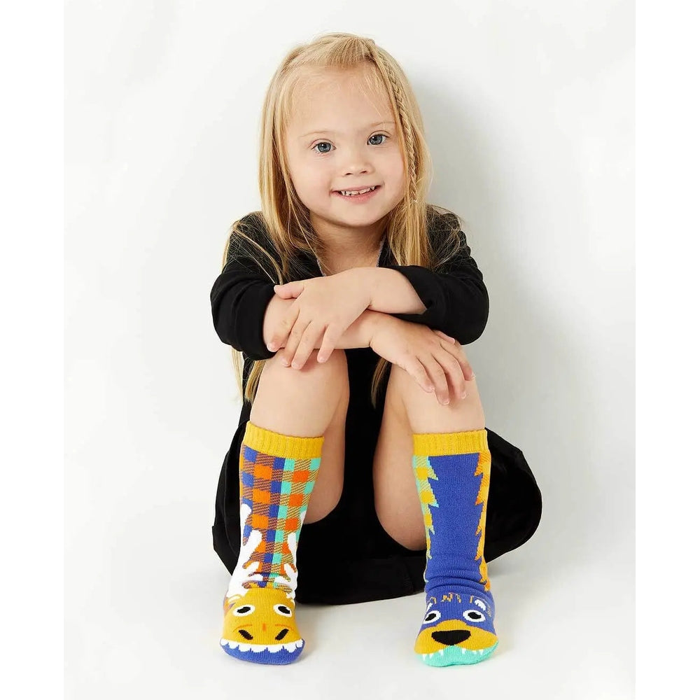 Pals Socks Moose&Bear Kids C on a smiling girl, colorful animal-face socks with yellow cuffs.