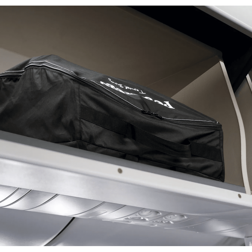 Peg Perego VOLO Travel Stroller bag in black with zipper and handles, stored on an aircraft overhead bin.