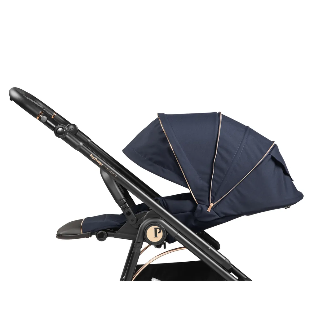Peg Perego Veloce stroller in navy with gold-trimmed canopy, shown with adjustable handle and foot muff.