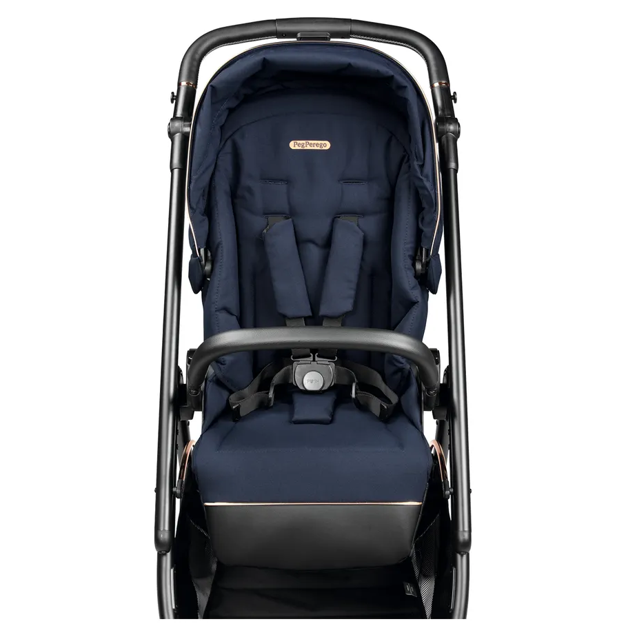 Peg Perego Veloce Stroller in navy with foot muff, padded harness secured for baby.