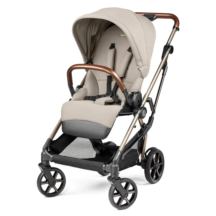 Peg Perego Vivace Stroller in beige with brown accents; harness secured and foot muff attached.