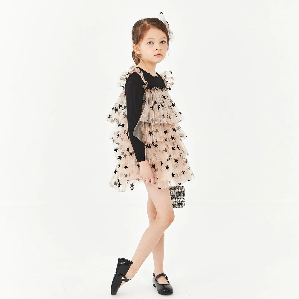 Petite Hailey Layered LS Tutu Black Star dress worn by a girl, nude tulle with black stars over a black top.