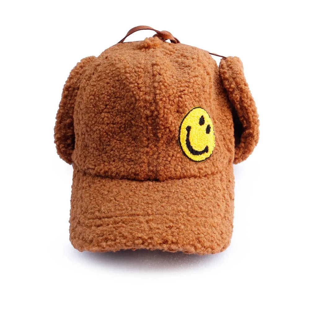 Petite Hailey Smile Ear Hat, brown faux-fur with ear flaps and a yellow smile patch, displayed upright.