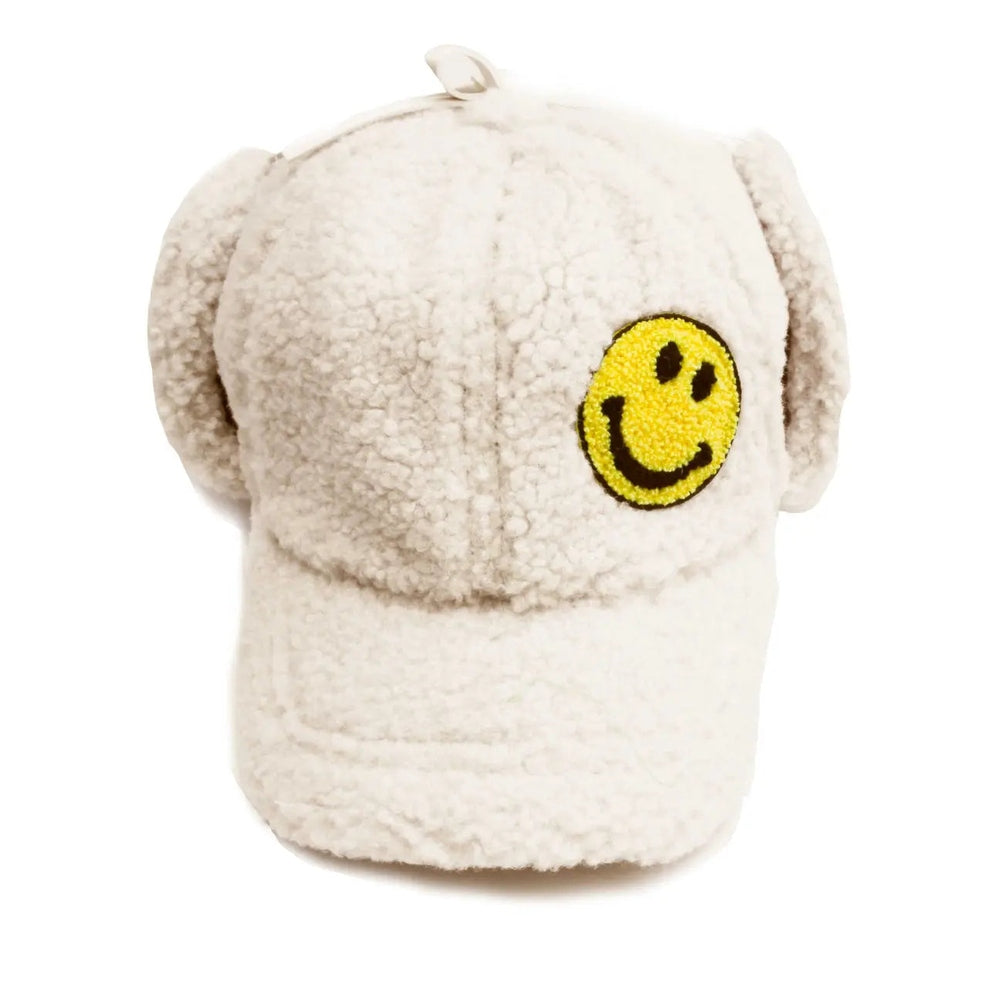 Petite Hailey Smile Ear Hat beige fluffy baby hat with yellow smiley patch on the front.