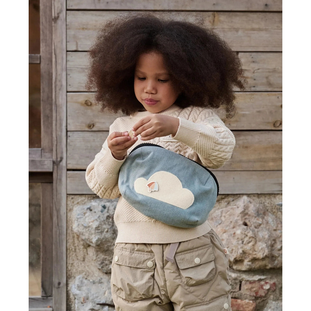 Petite Revery Corduroy Bumbag Dusk Blue worn by a toddler outdoors, as she opens the small zippered pouch.