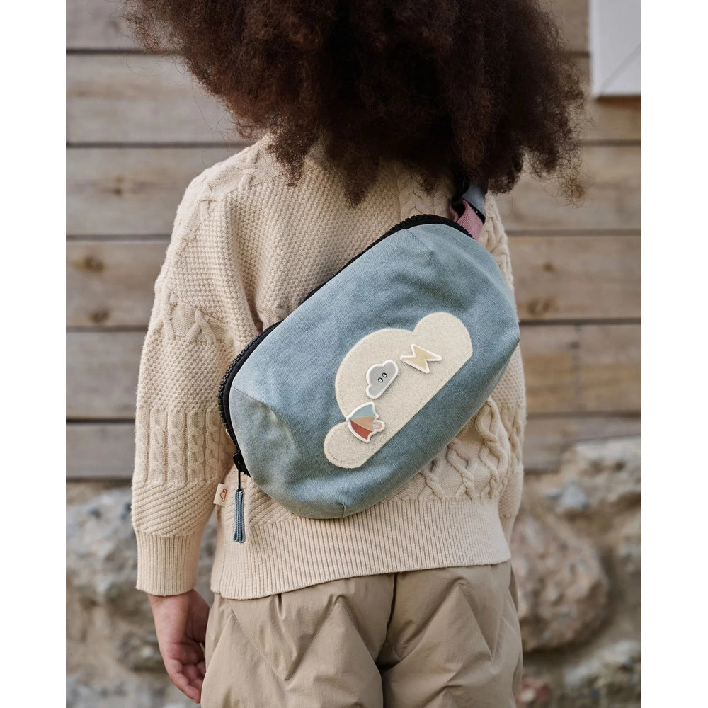 Petite Revery Corduroy Bumbag Dusk Blue worn crossbody by child, showing beige cloud patch embellishments.