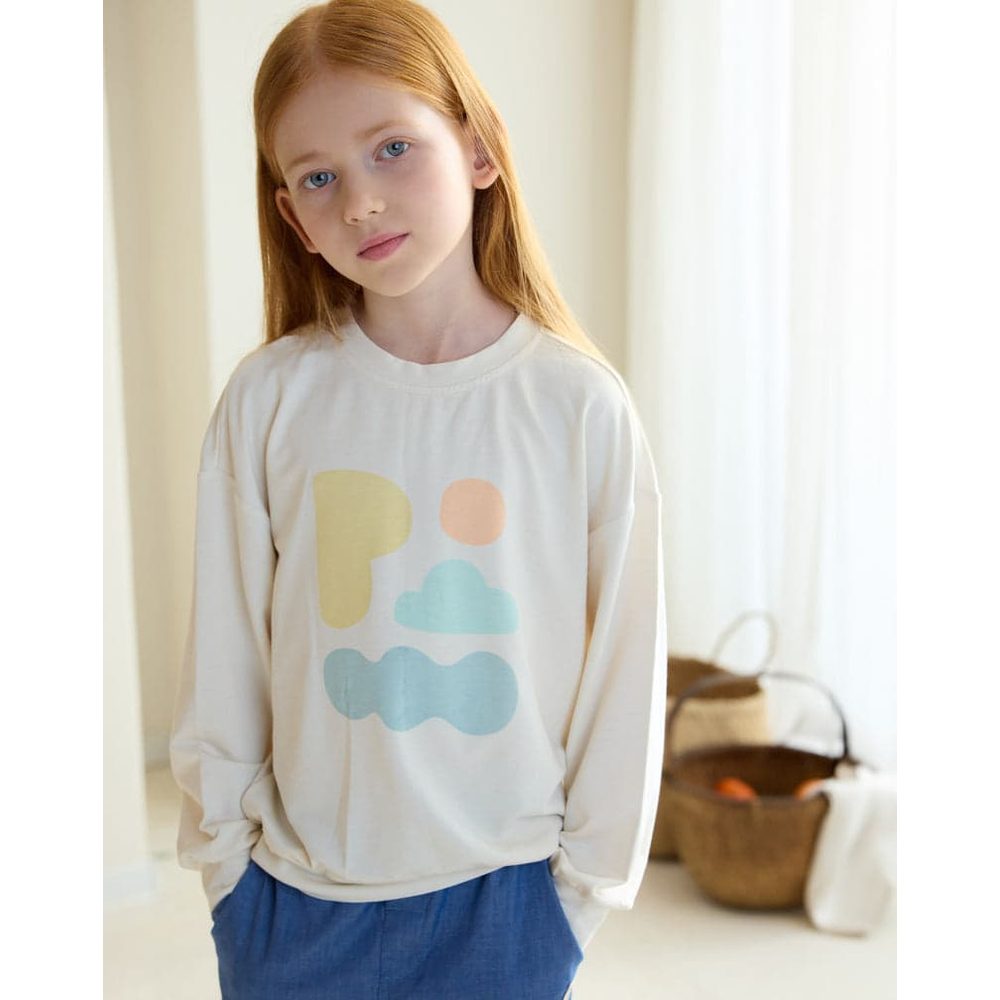 Petite Revery French Terry Drop Shoulder Long Sleeve Sweatshirt Jet Stream in cream with pastel cloud print, worn by a girl in a softly lit room.