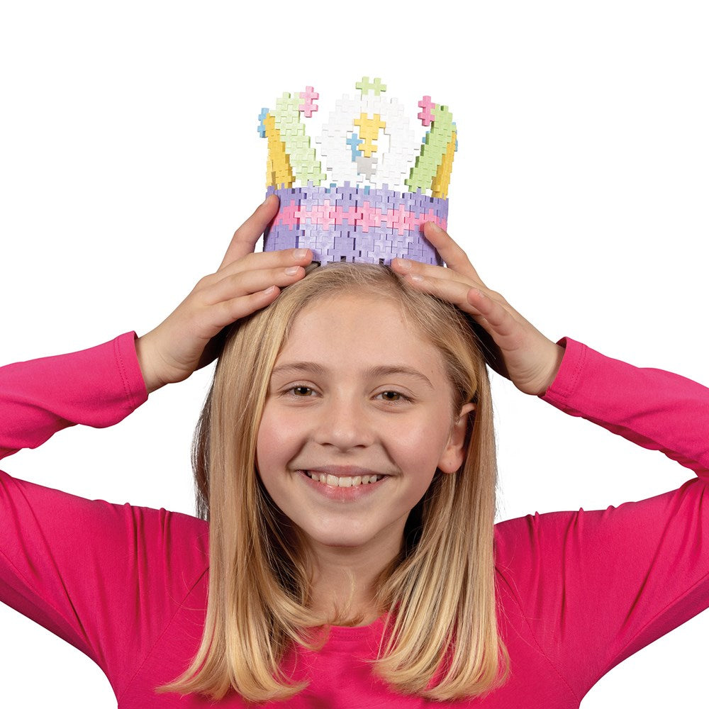 Plus-Plus pastel building bricks crown by PLUS-PLUS; 600-piece set worn by smiling girl