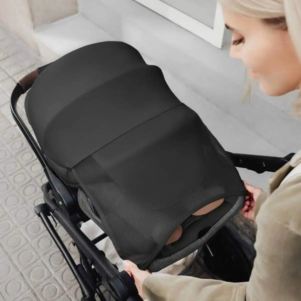 ROMER Juni Infant Car Seat with Versa Base in black, parent securing it to a stroller.