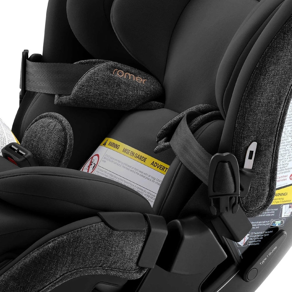 Romer Veni Convertible Car Seat in black/gray with 5-point harness and visible warning labels, ROMER branding.