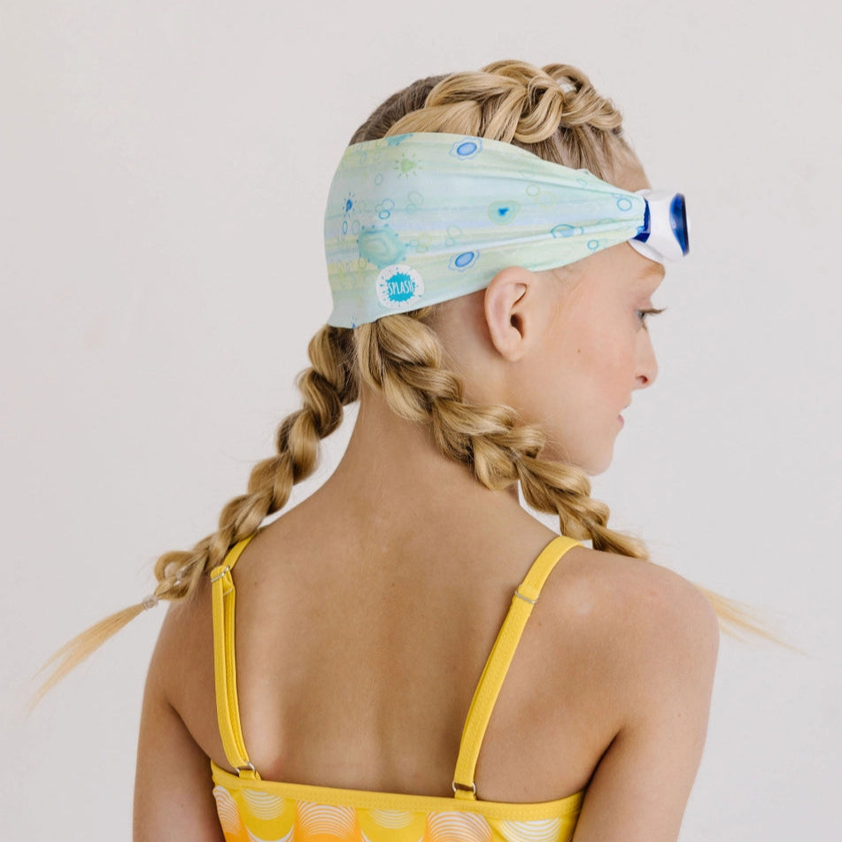 Splash Swim Goggles Sea Glass with blue frame worn on a light sea-glass patterned headband by a girl