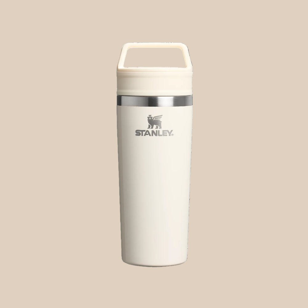 Stanley Café-To-Go Travel Mug 16 oz in white with built-in handle and secure lid, STANLEY logo visible.
