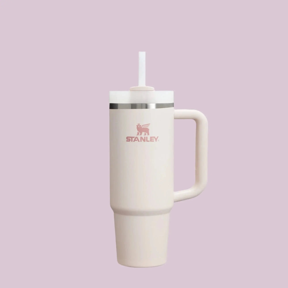 Stanley The Quencher H2.0 Flowstate 30 oz tumbler in cream with pink logo, straw lid, and side handle held upright