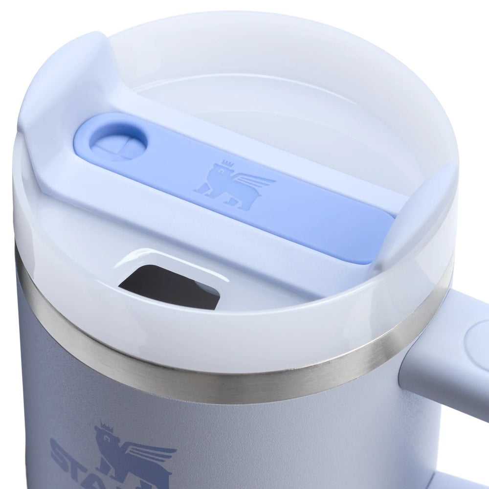 Stanley The Quencher H2.0 Flowstate 20 oz tumbler with handle, white body and light blue lid showing the flip-top lid in use.