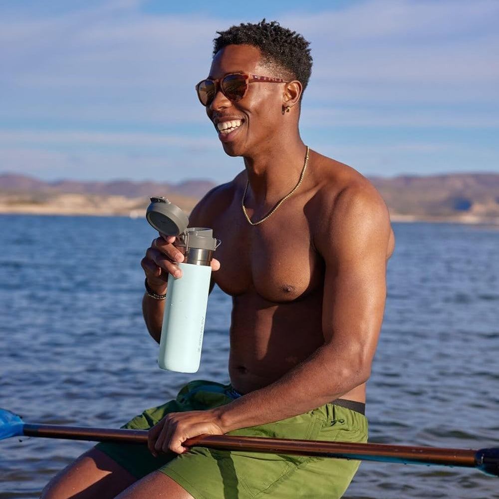 Stanley The Quick Flip GO Bottle 24 oz in light blue, flip-top lid shown, held by a smiling man on a boat.