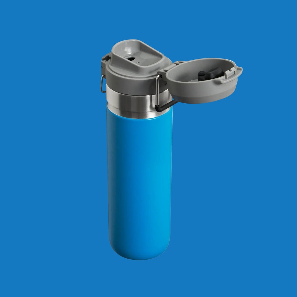 STANLEY The Quick Flip GO Bottle 24 oz blue stainless steel with gray flip-top lid being opened.
