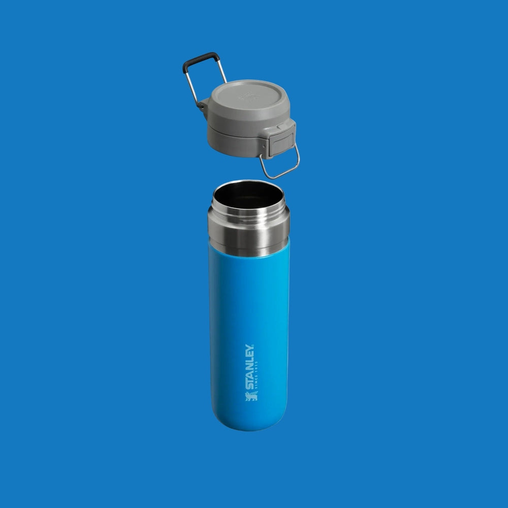 Stanley The Quick Flip GO Bottle 24 oz blue stainless steel water bottle with gray flip-top lid lifted off.