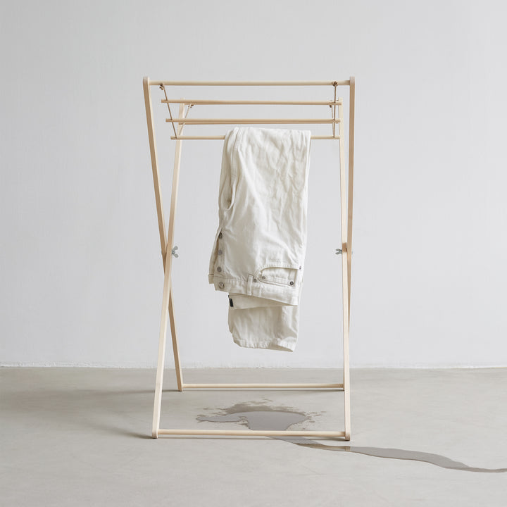 Tangentgc Oud Denim Wash 500 ml bottle displayed with white denim jeans on a wooden clothes rack