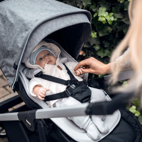 Thule Shine stroller in gray fabric with infant secured in harness