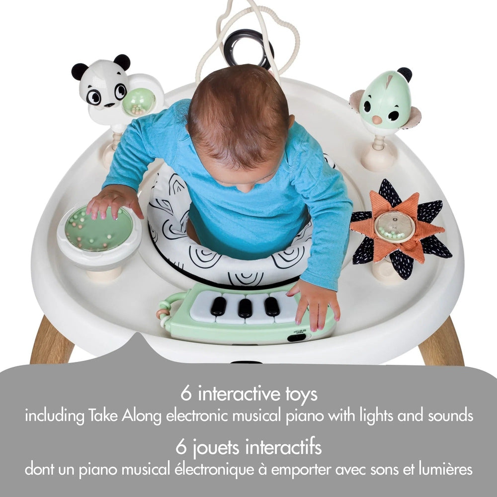 Tiny Love 5-in-1 Here I Grow stationary activity center; baby taps green piano keys amid hanging panda and flower toys.