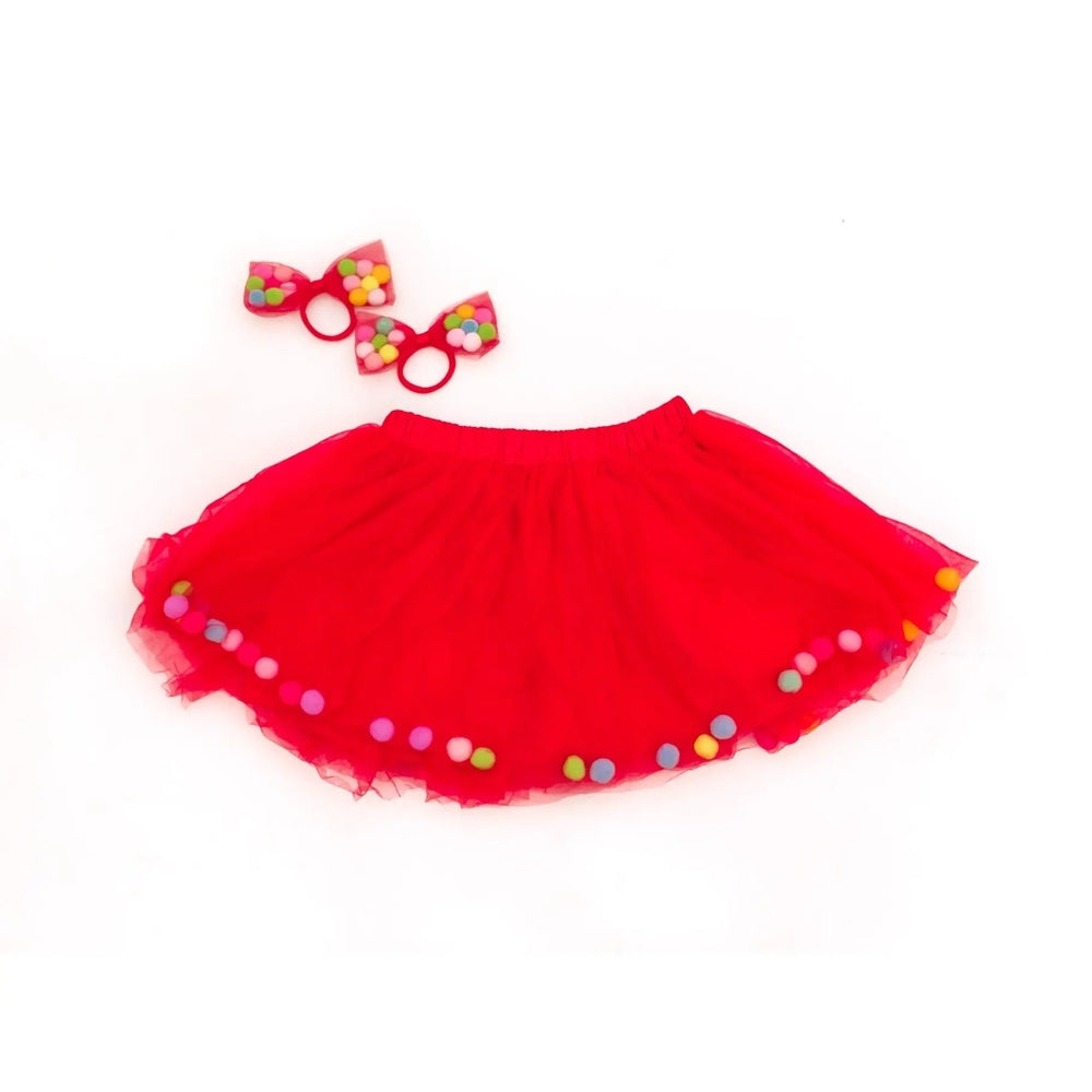 Tutu Joli LLC 2pc Red Christmas kids tutu set with colorful pom-pom trim and matching bow hair ties, laid flat.