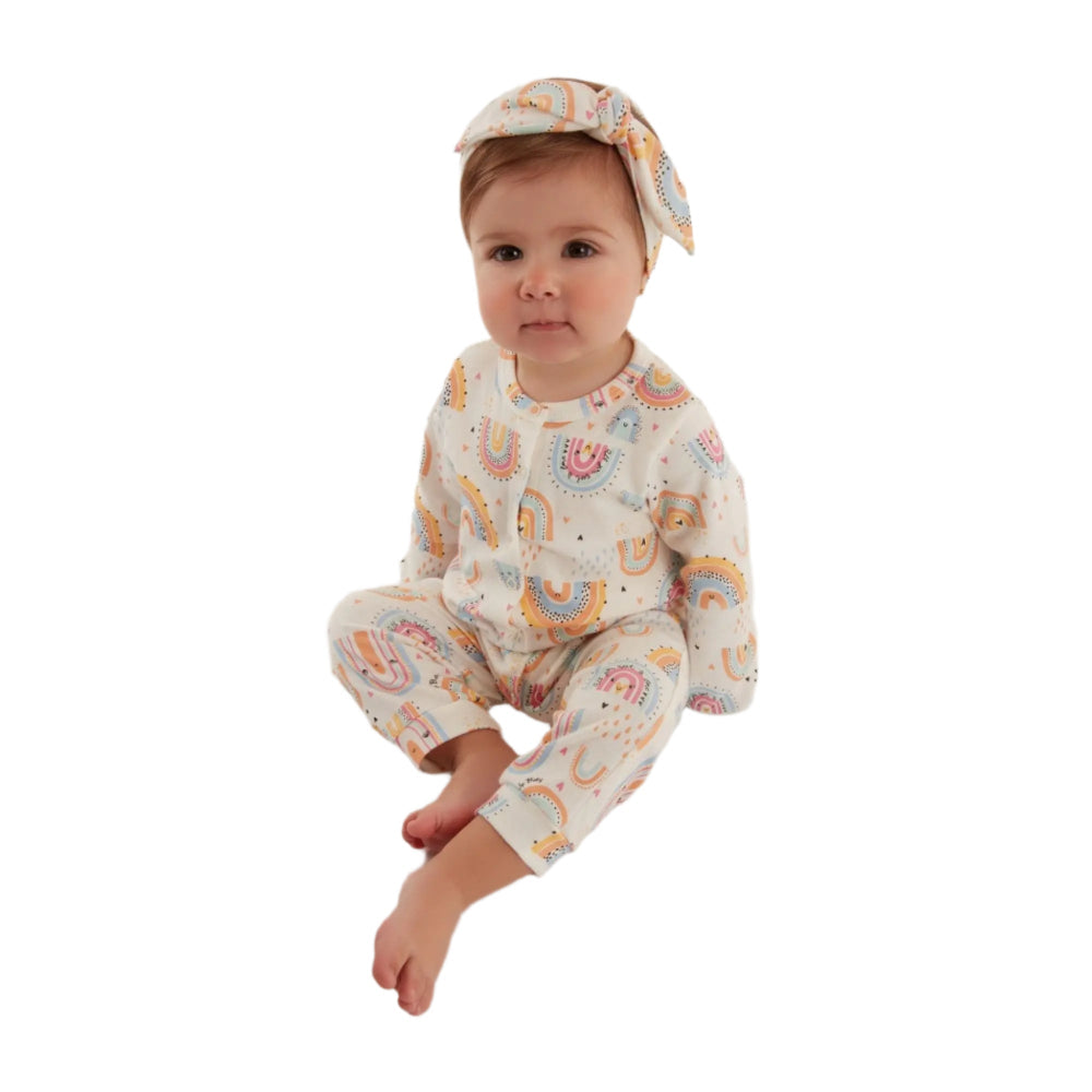 UP Baby Girls Jumpsuit Off White AB1495 with pastel rainbow print, baby girl sitting barefoot in a matching headband.