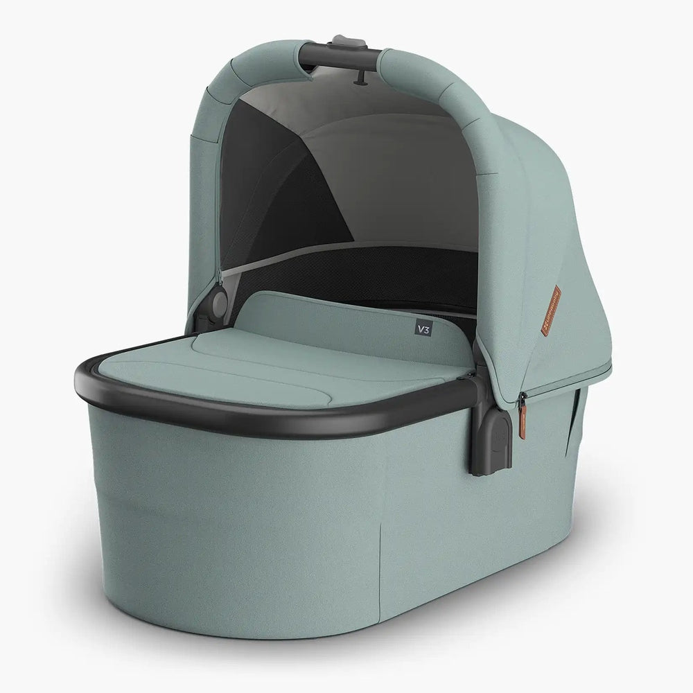 Uppababy Bassinet V3 in teal with canopy over a cushioned bassinet and built‑in carry handle.